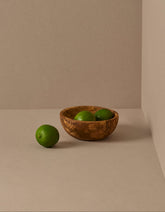 A set of natural olive wood bowls in various sizes, with the smallest bowls containing lemons. The bowls display a beautiful wood grain pattern.